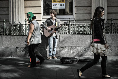 People standing on sidewalk against wall