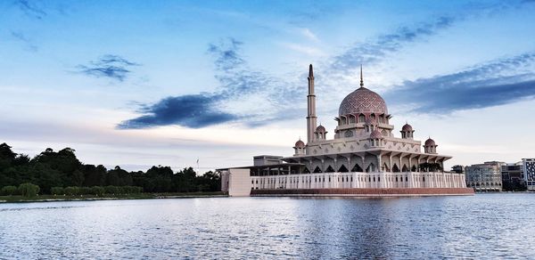 View of lake with buildings against cloudy sky