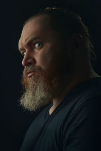 Side view of man looking away against black background