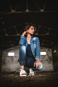 Young woman looking away while sitting on floor