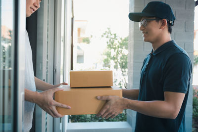Delivery person giving packages on man while standing at entrance