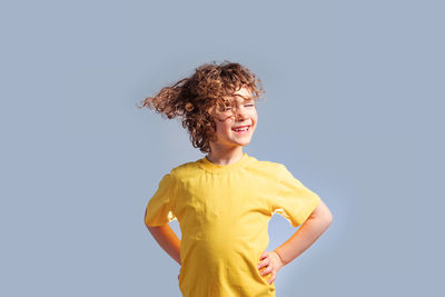 Young woman looking away while standing against gray background