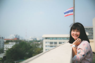 Portrait of smiling woman in city against sky