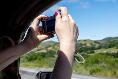 Cropped hand of woman photographing through car