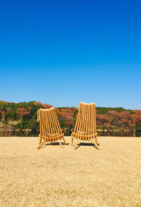 Empty chairs and tables against clear blue sky