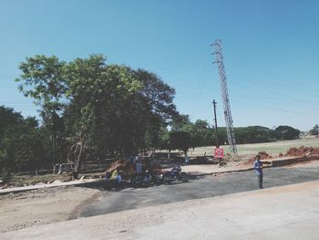 People by the road against clear sky