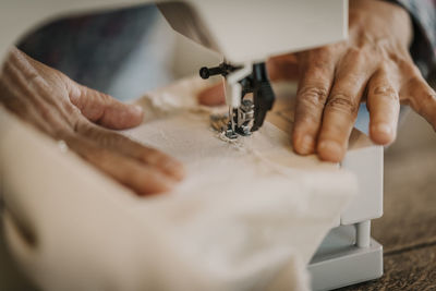 Woman sewing piece of fabric through sewing machine