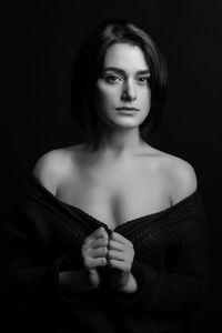 Portrait of woman wrapped in shawl standing against black background