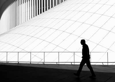 Silhouette man walking on footpath in city