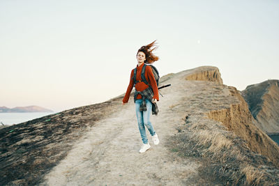 Portrait of man standing on rock against sky