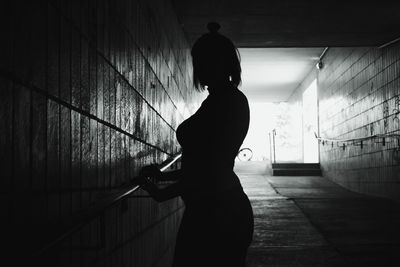 Silhouette of woman holding railing in underground walkway