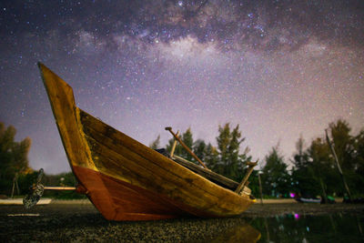 Fishing boat on beach against sky at night