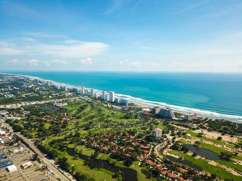 Aerial view of city by sea against sky