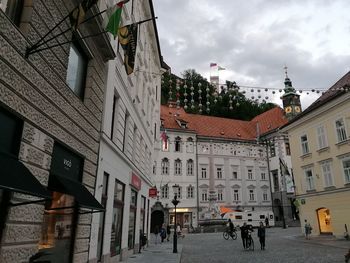 People on street amidst buildings in city against sky