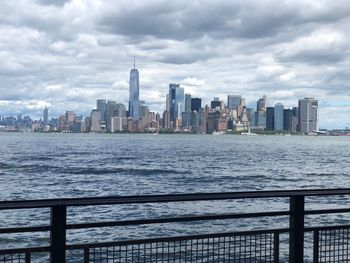 View of buildings at waterfront against cloudy sky