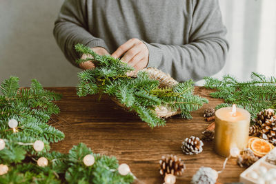 A male florist makes a new year's wreath with fresh fir branches, pine cones and dried fruits.