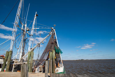 Sailboats moored in sea against blue sky