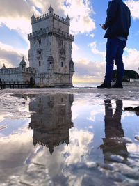 Reflection of a historic building and a man in a puddle