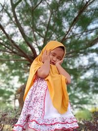 Midsection of little girl standing against trees