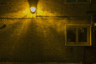 Illuminated street light against wall at night