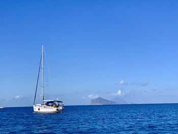 Sailboat sailing on sea against blue sky