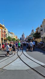 People on city street by buildings against sky