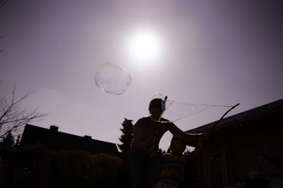 Low angle view of man standing at bubbles against sky