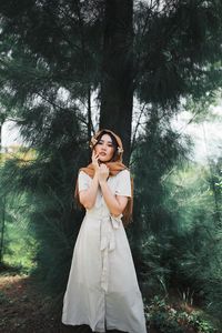 Portrait of woman standing by tree