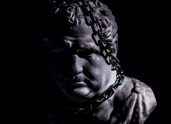 Close-up statue with chain against black background