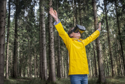Woman wearing virtual reality headset standing in a forest