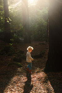 Little child walking in forest with beautiful light
