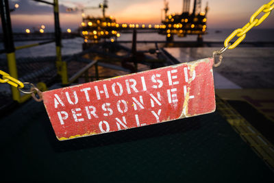 Close-up of safety or warning sign hanging on railing of a construction work barge at oil field