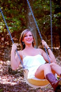 Portrait of a smiling young woman on swing