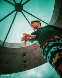 Low angle view of man holding umbrella against sky