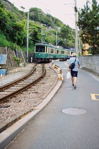 Rear view of man walking on railroad track