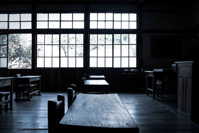 Empty chairs and table against window