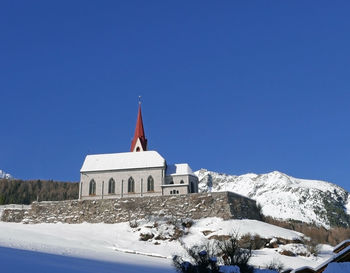 Church by building against clear sky during winter