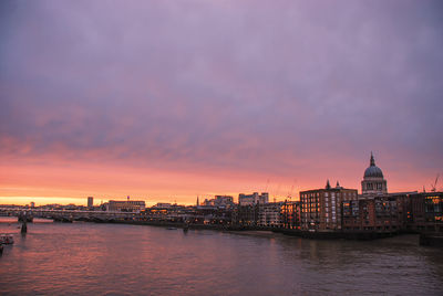 View of buildings by river against cloudy sky