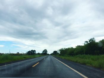 Road by trees against sky
