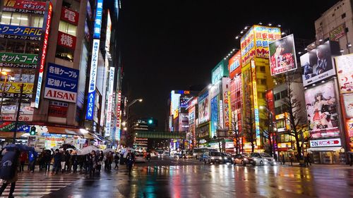 People on street with illuminated billboards on buildings at akihabara