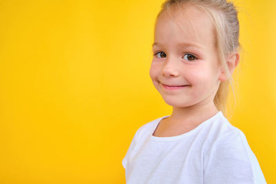 Portrait of young woman against yellow background