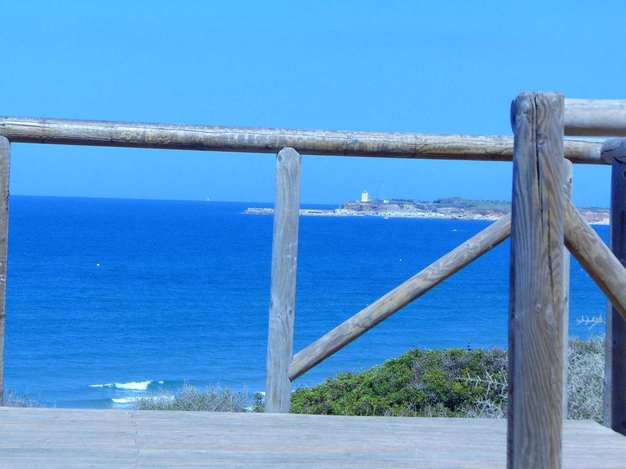 RAILING BY SEA AGAINST CLEAR BLUE SKY