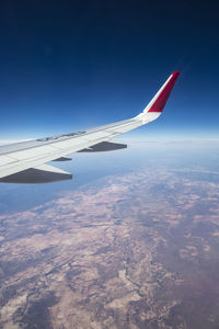 Aerial view of airplane wing against blue sky