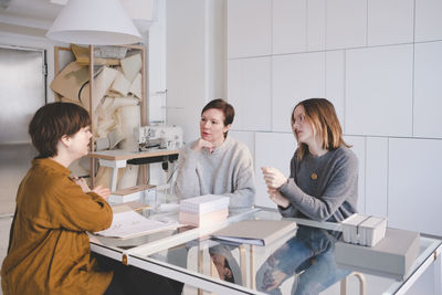 Female design professionals having discussion at desk in workshop