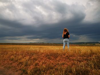 Rear view of man standing on field against sky