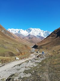 Scenic view of snowcapped mountains against clear blue sky