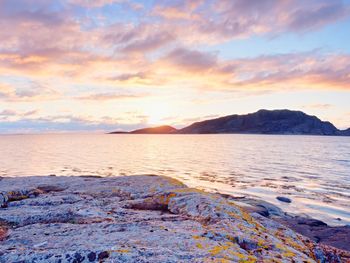 Beautiful sunrise on rocky shore and dramatic sky clouds. reflection and flare