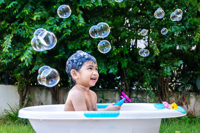 Full length of shirtless boy with bubbles