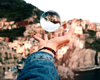 Midsection of woman holding crystal ball with cityscape in background