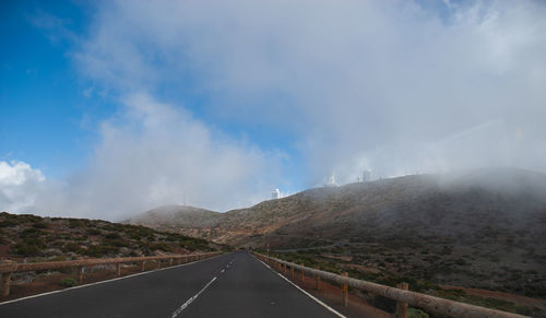 Road leading towards mountain against sky